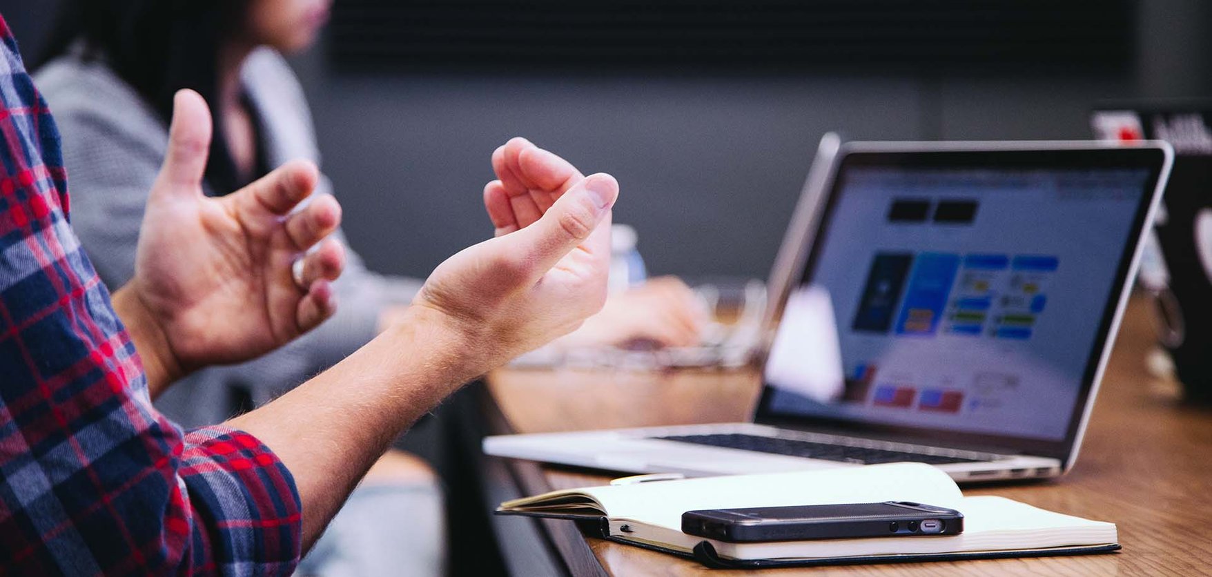 A person gesturing with their hands in front of a laptop screen