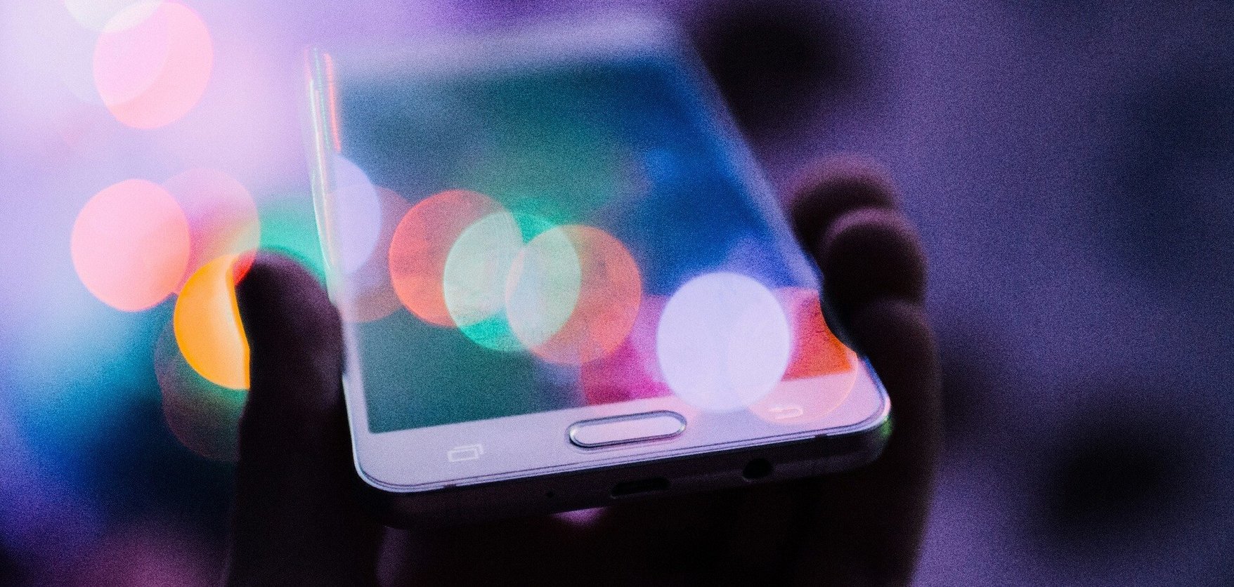 Hand holding phone with colourful light flares