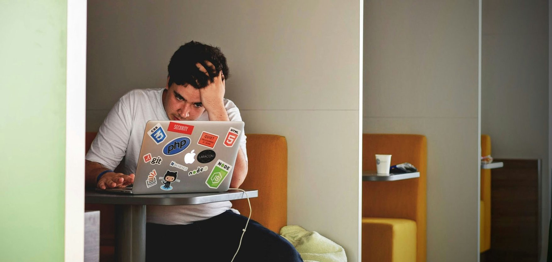 A man sitting in front of his laptop with his head in his hands